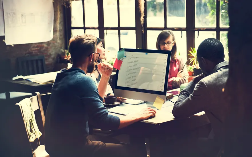 Test lead guiding a QA team around a shared workstation