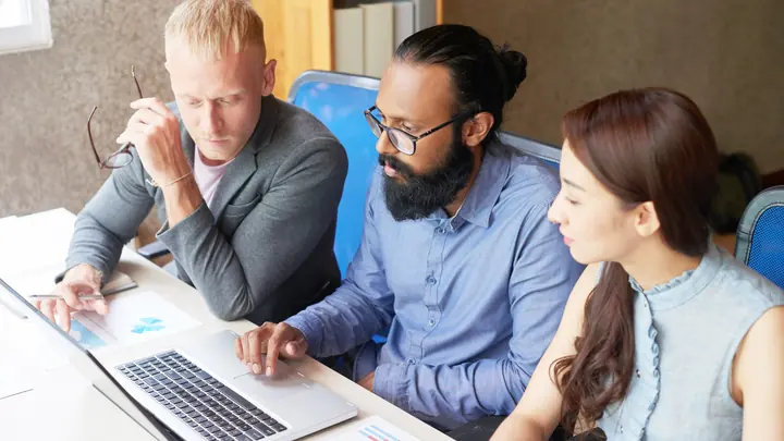Manual testing team collaborating around a laptop