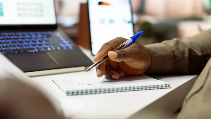 Test manager writing planning notes at a workstation